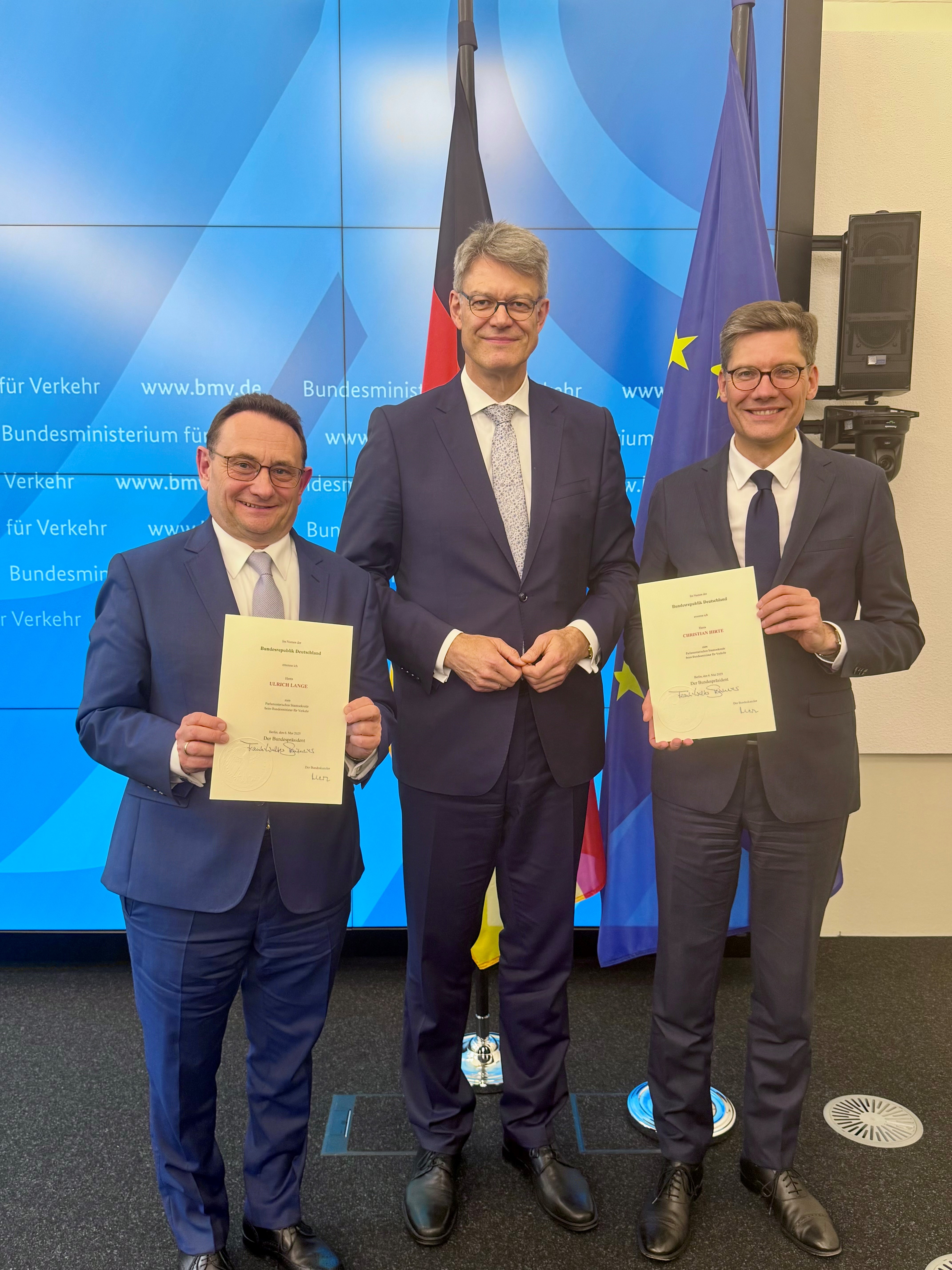 Ulrich Lange (l.) erhält die Urkunde vom neuen Verkehrsminister Patrick Schnieder (M.).