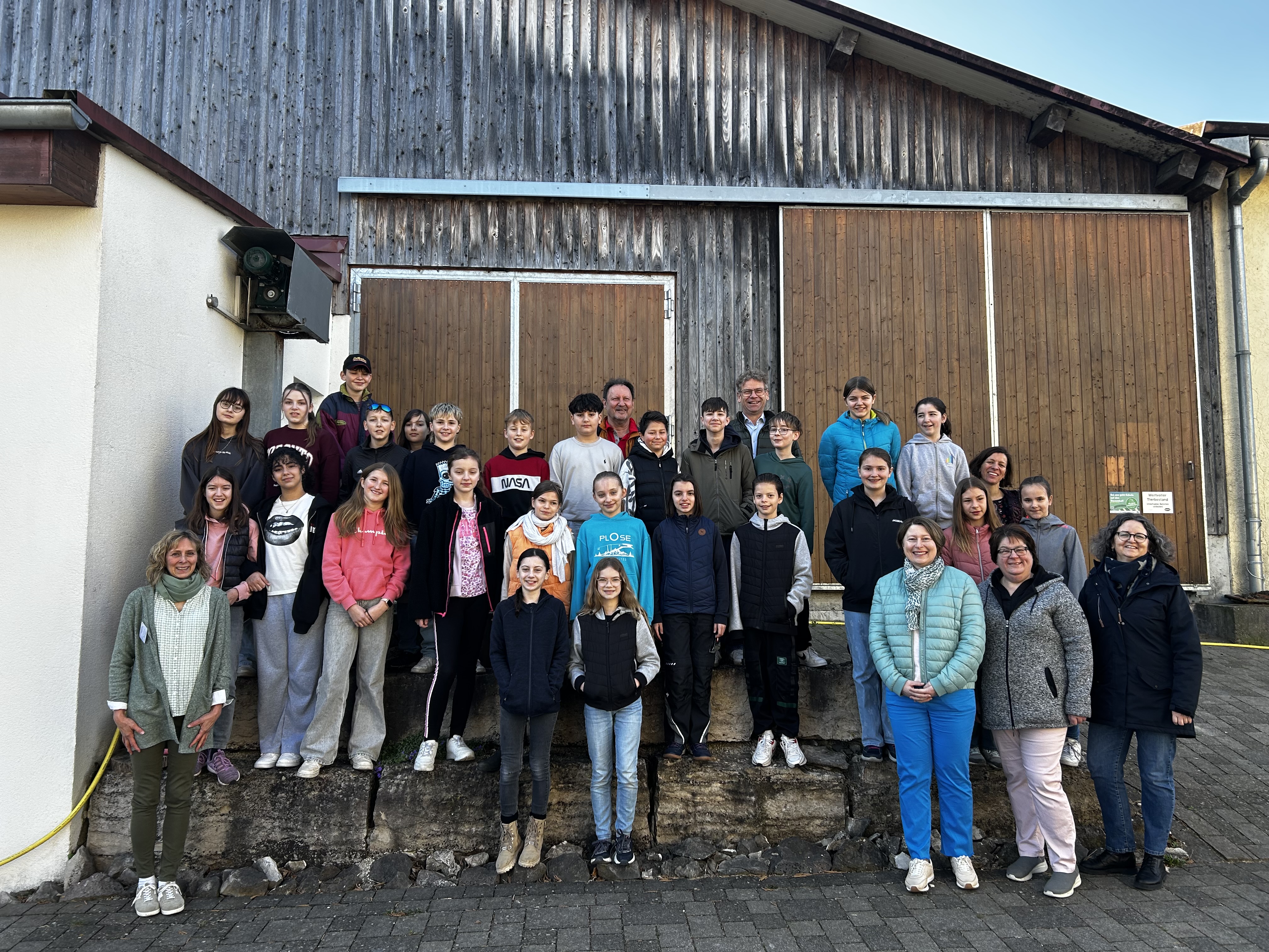 Auf dem Bauernhof von Familie Leinfelder lernten die Schülerinnen und Schüler der örtlichen Realschule im Rahmen des Programms „Erlebnis.Bauernhof“ viel Wissenswertes rund um das Thema Milch, Kuh und Getreide. Begleitet wurden sie dabei von ihrem Lehrer Gerhard Reissig (hinten 1. von li.), Auf dem Foto zudem: Behördenleiter Dr. Reinhard Bader (hinten 2. von li.), Edith Auchter (AELF, vordere Reihe, 1. v.l.n.r.), Vizelandrätin Claudia Marb (vordere Reihe, 2. v.l.n.r.), Stellvertretende Kreisbäuerin Susanne L