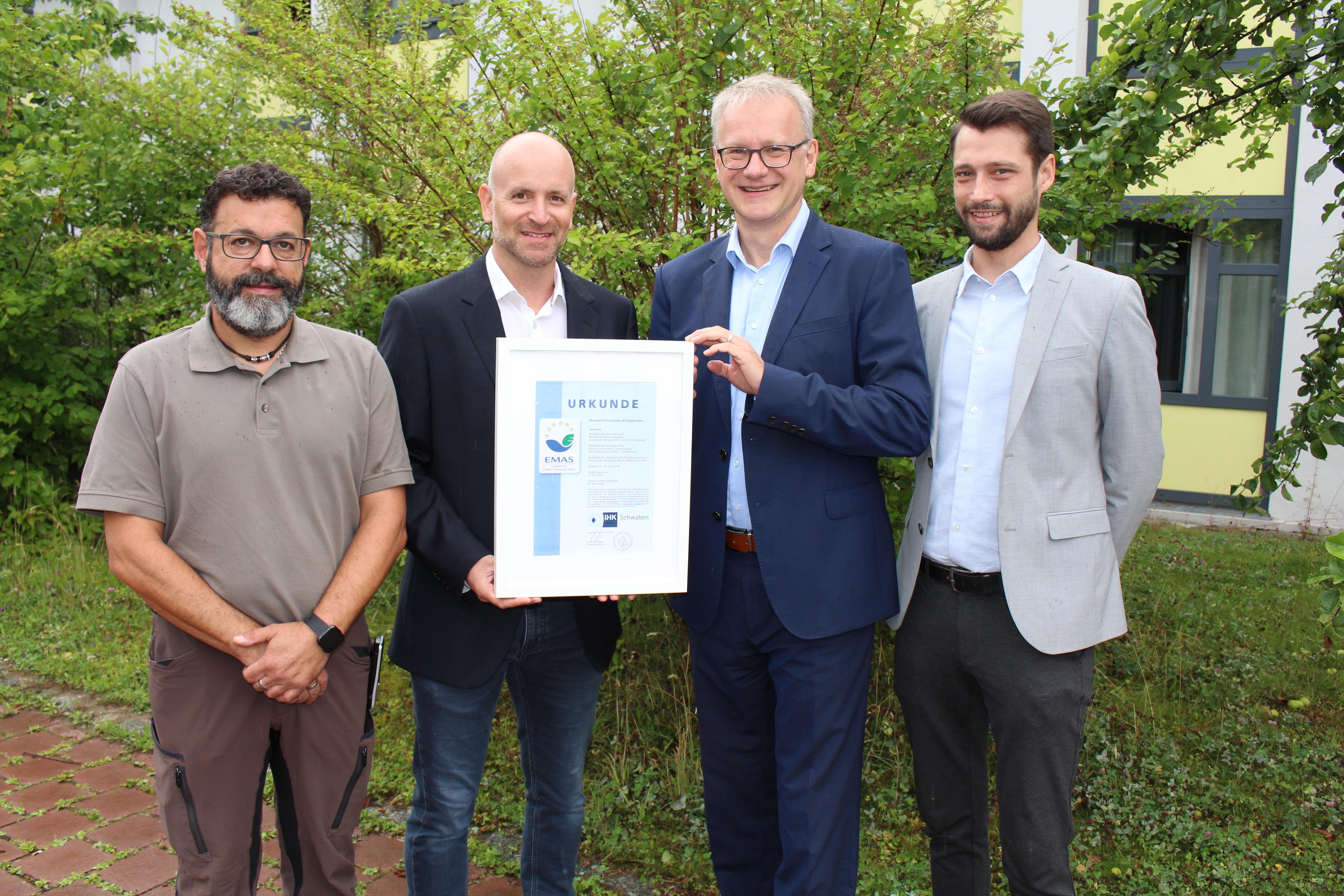 IHK-Regionalgeschäftsführer für den Wirtschaftsraum Augsburg, Jens Walter (Zweiter von rechts), überreichte (von links) Paul Pirisino, Stefan Reitsam und Fabian Malz (alle Bezirkskliniken Schwaben) die EMAS-Urkunde.