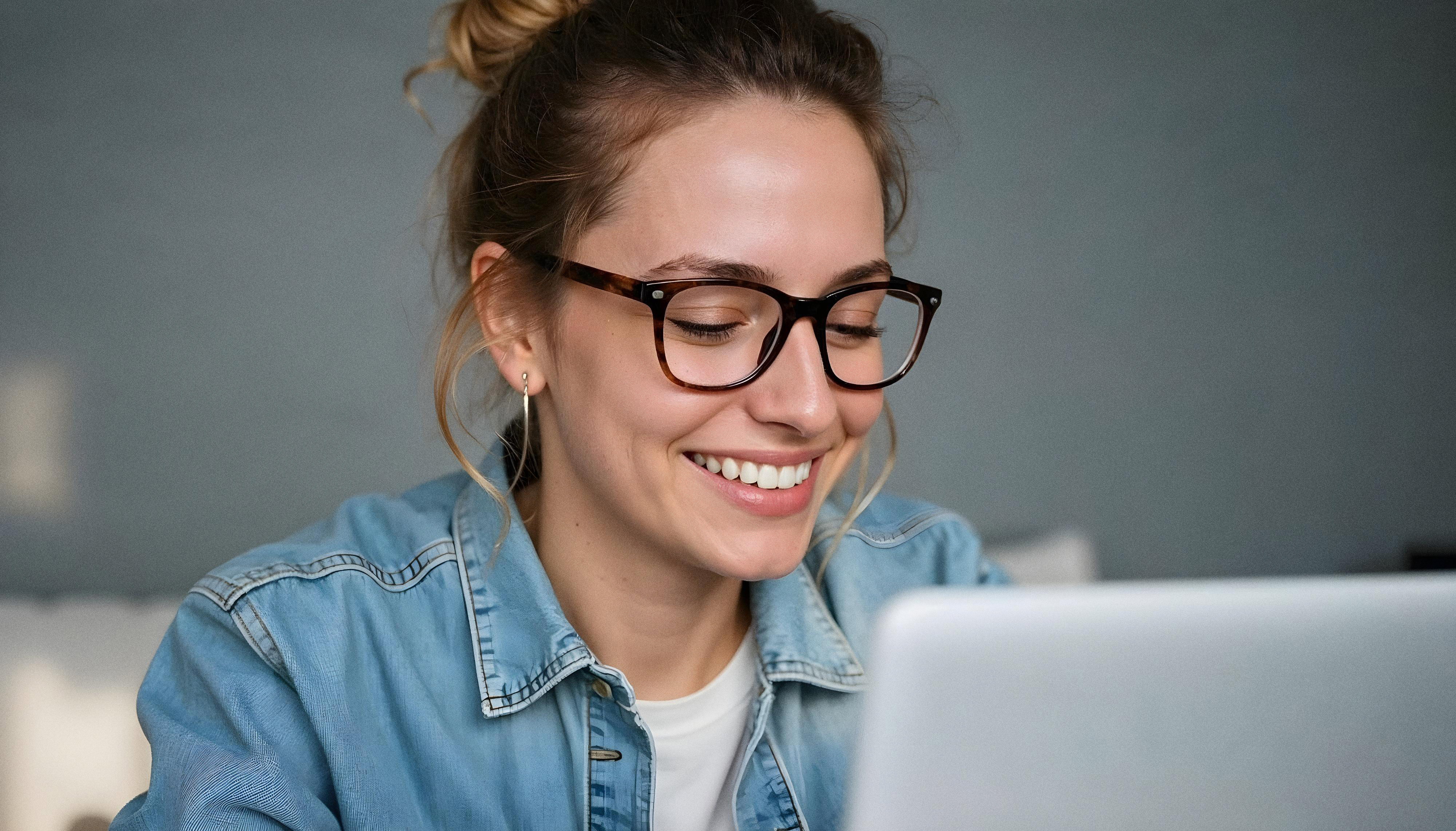 Eine Frau mit Brille arbeitet an einem Laptop.