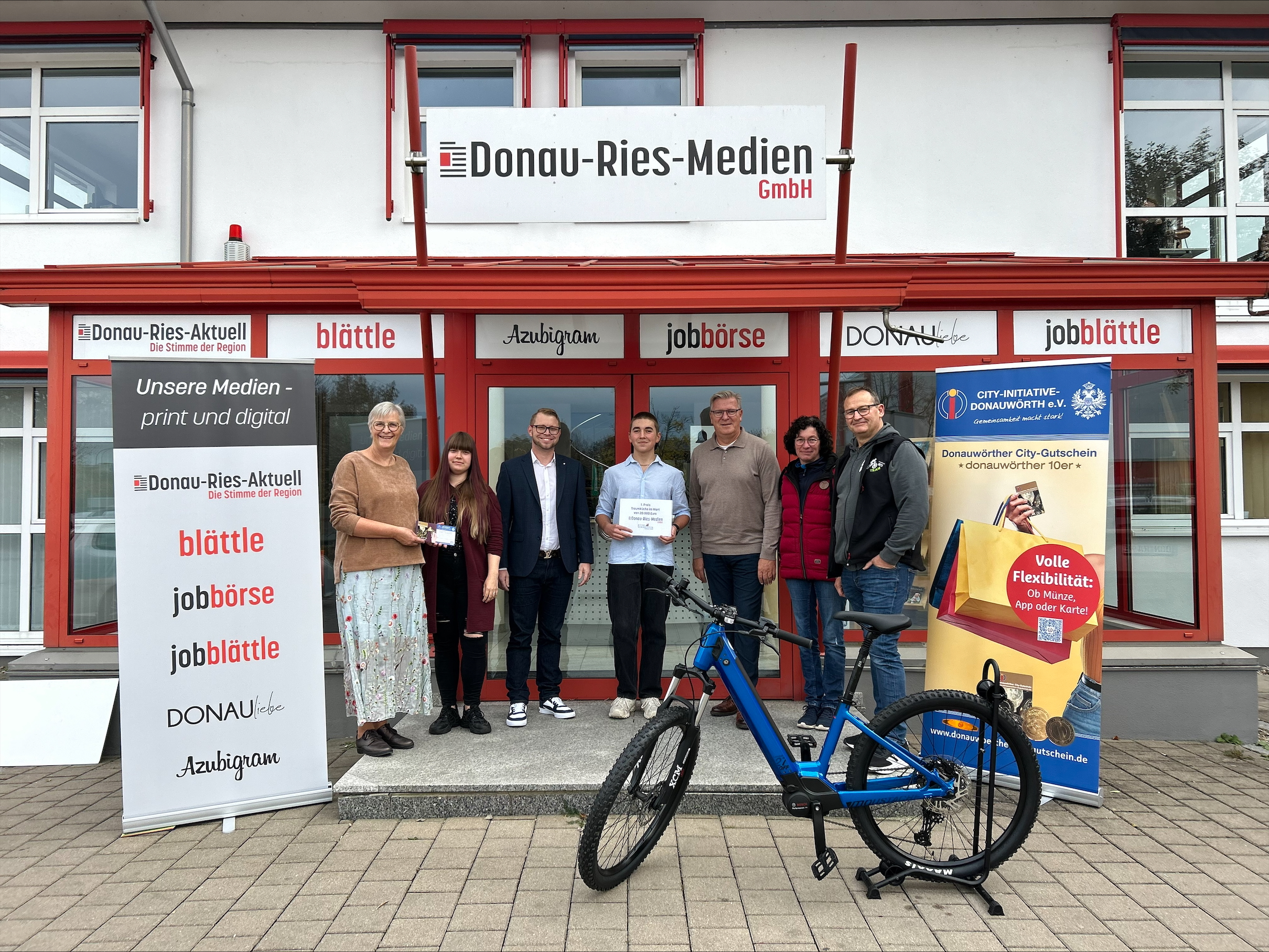 Von links sind folgende Personen zu sehen: Christiane Kickum (Fachbereichsleitung Kultur und Stadtmarketing, CID), Sarah Braun (Gewinnerin des 250 Euro City-Gutschein), Matthias Stark (Geschäftsführer der Donau-Ries-Medien GmbH), Simon Schmid (Gewinner der 20.000 Euro Traumküche), Heinz Dallmaier (Geschäftsführer der Küche & Wohnkultur Dallmaier GmbH), Inge Knötzinger (Gewinnerin des E-Bikes), Simon Bayer (Mitarbeiter E-Biker Stable Deiningen).